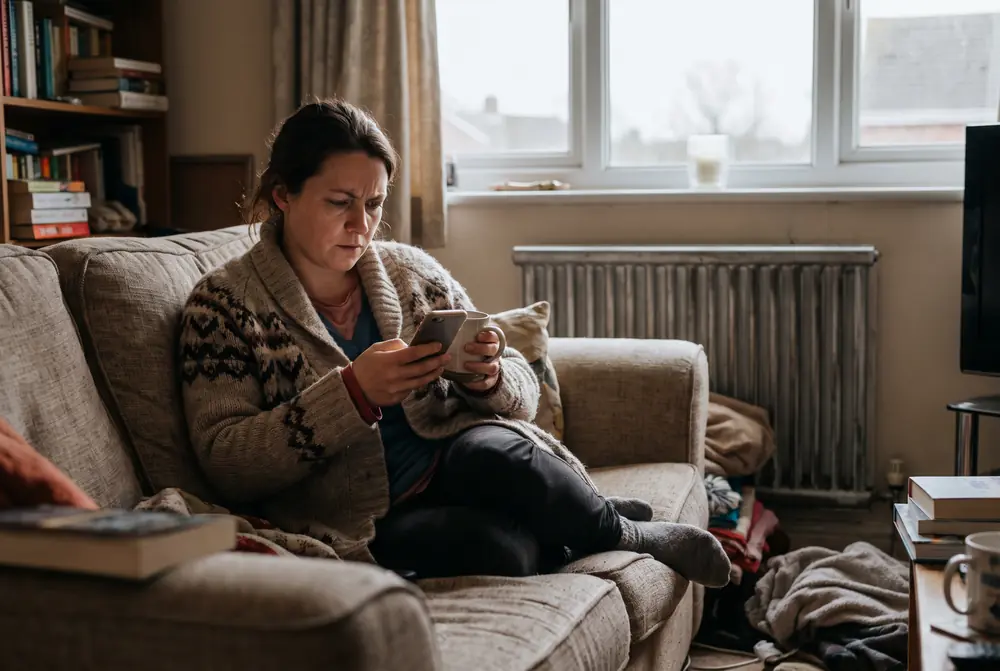 A woman on her sofa searching on her phone